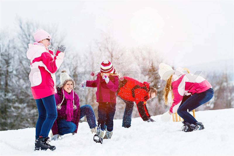 Family with kids having snowball fight in winter, stock photo