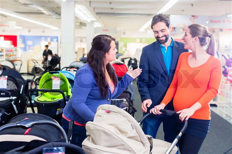 Woman, man, and sales lady in baby store testing buggy, stock photo