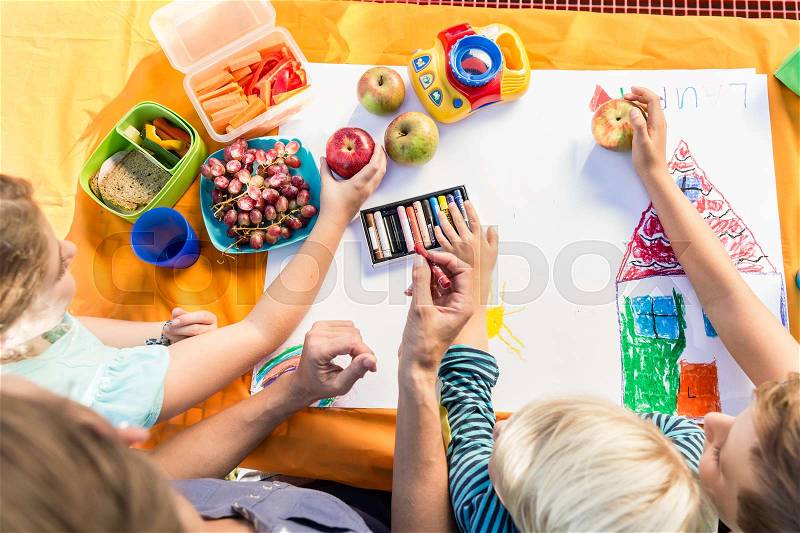 Schoolgirls and schoolboys painting during lunch break with fruits and sandwich, stock photo