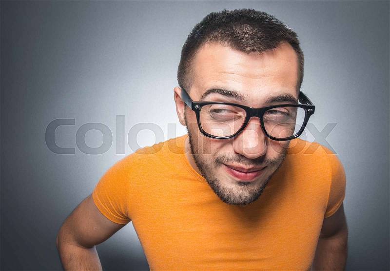 Funny careful young man. Pensive guy thinking and looking to side, isolated on gray bacground with copy space for text, stock photo