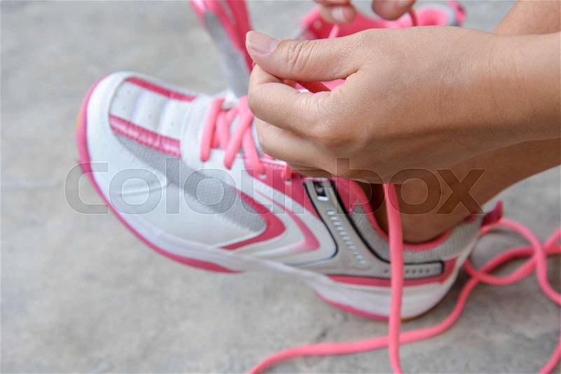 Woman is put on the pink sport shoes, stock photo