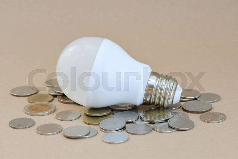 Concept of LED bulb with coins - the choice of saving technology, stock photo
