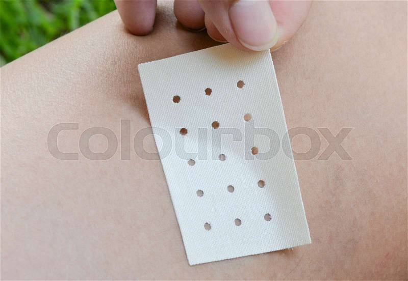 Human hand is sticking the menthol plaster to skin, stock photo
