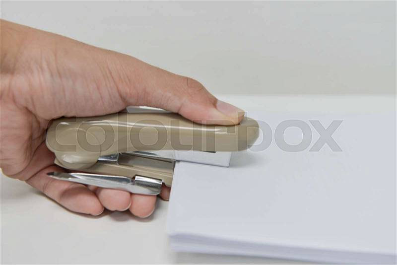 Human hand is stapling the paper with stapler, stock photo