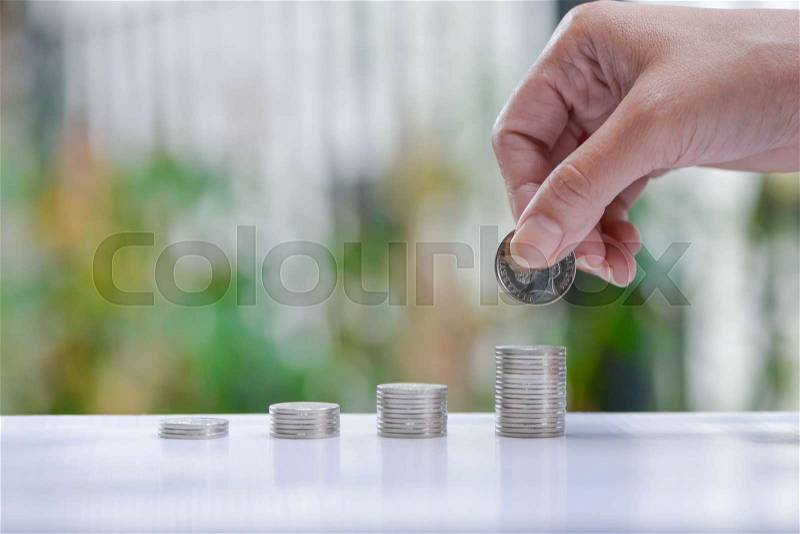 Woman hand putting coin to growing coins stacks - Concept of saving money, stock photo