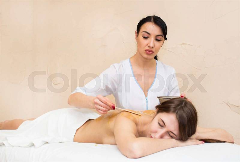 Girl treatment massage honey body wrap in a beauty salon, stock photo