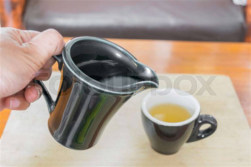 Pouring tea into cup of tea, stock photo