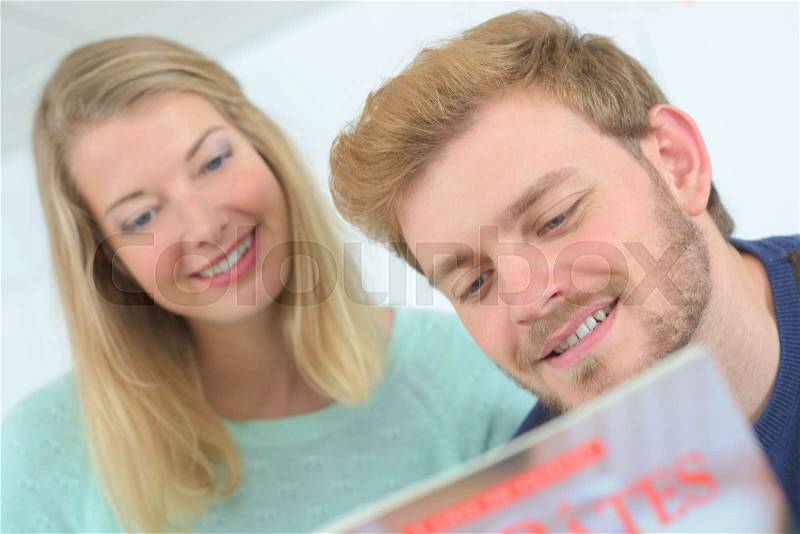 Couple following recipe from a magazine, stock photo