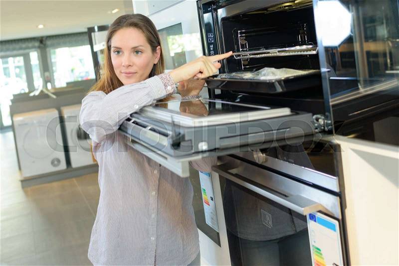 Woman looking at ove in home appliance store, stock photo