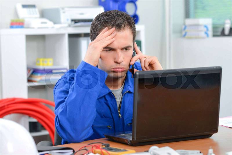 Frustrated man on telephone, looking at computer, stock photo
