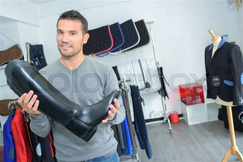 Man in shop holding riding boot, stock photo