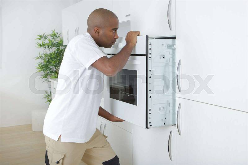 Man fitting new oven in kitchen, stock photo
