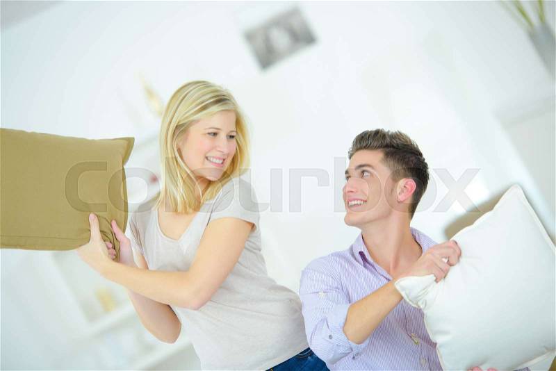 Playful couple having a pillow fight, stock photo