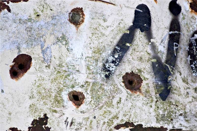 Closeup of rusted metal with chipped paint and bullet holes, stock photo