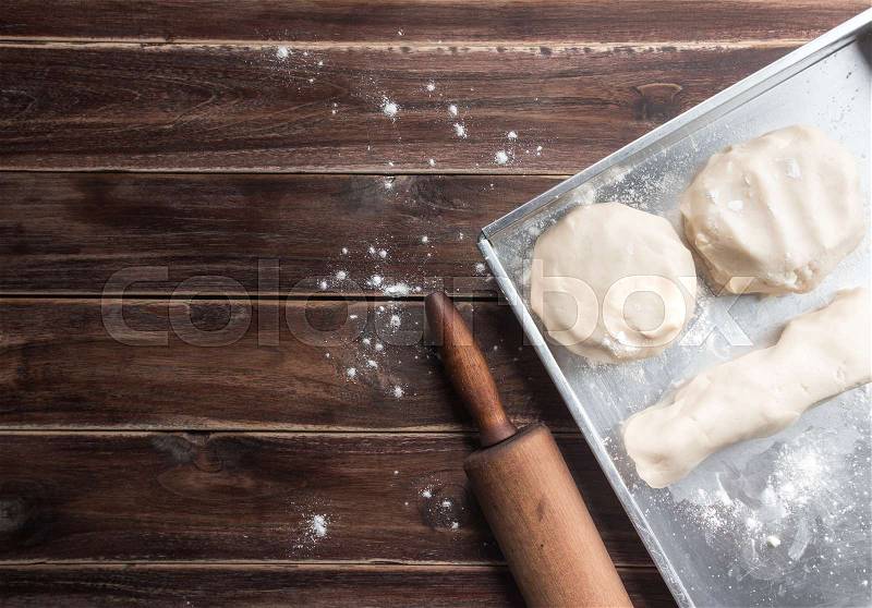 Dough and wooden rolling pin with dusting of flour on rustic wooden background,top view, stock photo