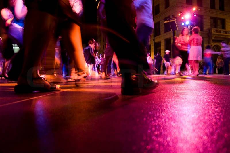 A low shot of the dance floor with people dancing under the colorful lights, stock photo