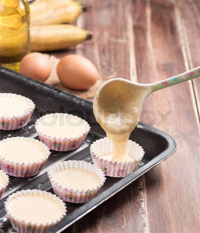 Pouring banana cake into preparing cupcakes, stock photo