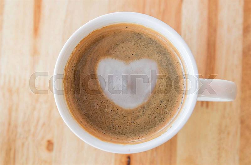Heart in cup of coffee with in a white cup on wooden background, stock photo