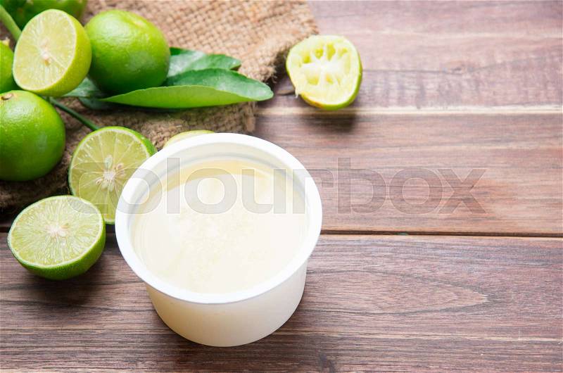 Freshly squeezed lime juice with lime fruits on wood table, stock photo