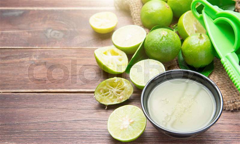 Freshly squeezed lime juice with lime fruits on wood table, stock photo