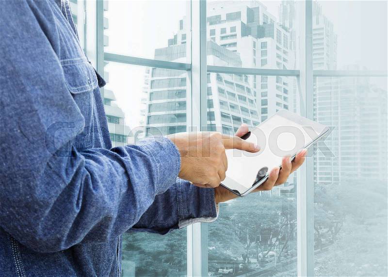 Businessman using digital tablet with modern building , stock photo