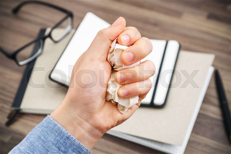 No idea with crumpled paper ball in hand on office table, stock photo
