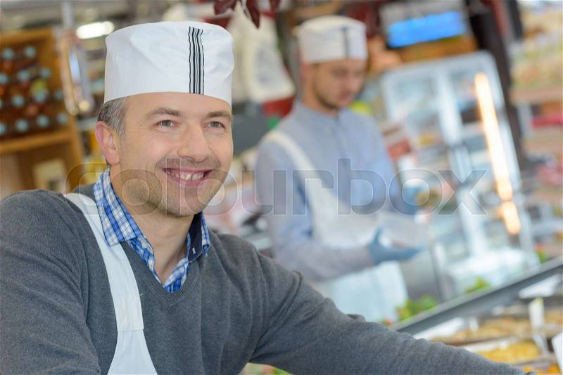 Butcher teaching a young one how to sell meat, stock photo