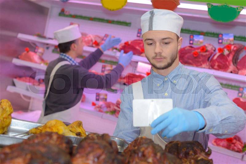 Butcher teaching a young one how to sell meat, stock photo