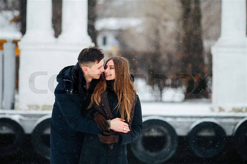 Guy hugging his girlfriend from behind in the park, in winter holidays, stock photo
