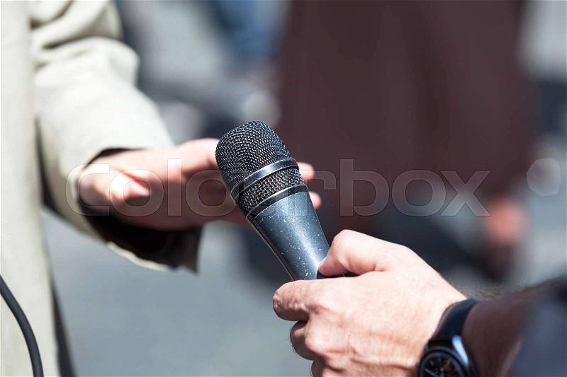Journalist holding a microphone conducting an TV or radio interview, stock photo
