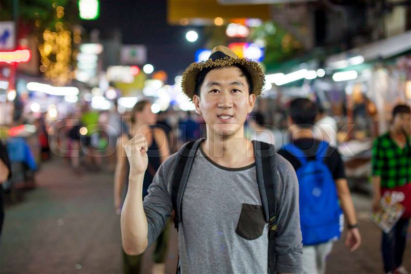 Asian tourist pointing at the back in Asia night market, stock photo