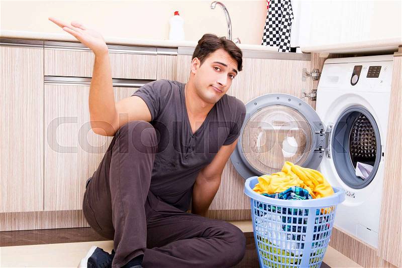 Young husband man doing laundry at home, stock photo