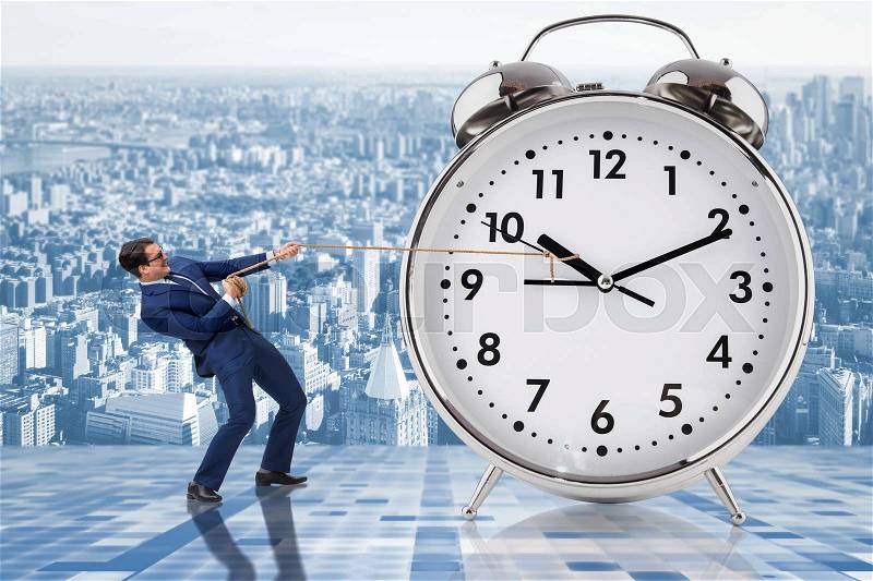 Businessman pulling clock in time management concept, stock photo
