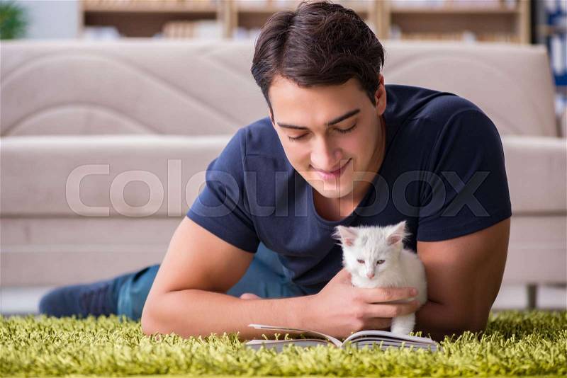 Young handsome man playing with white kitten, stock photo