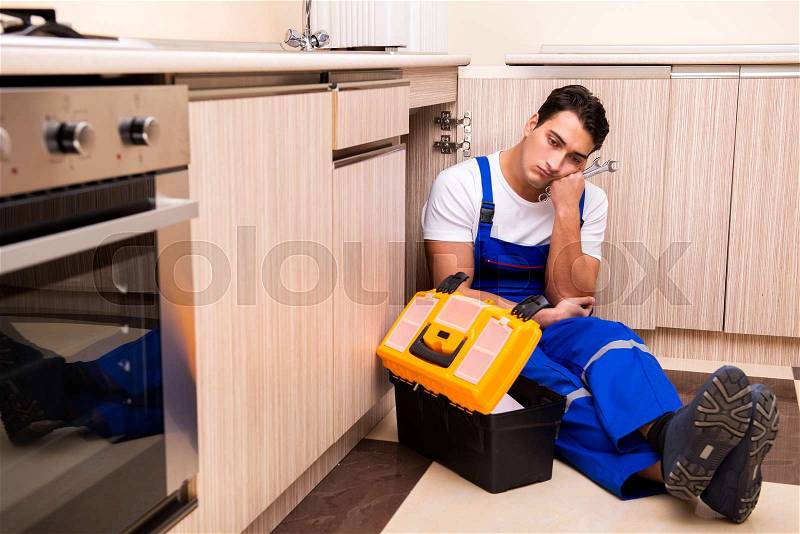 Young repairman working at the kitchen, stock photo