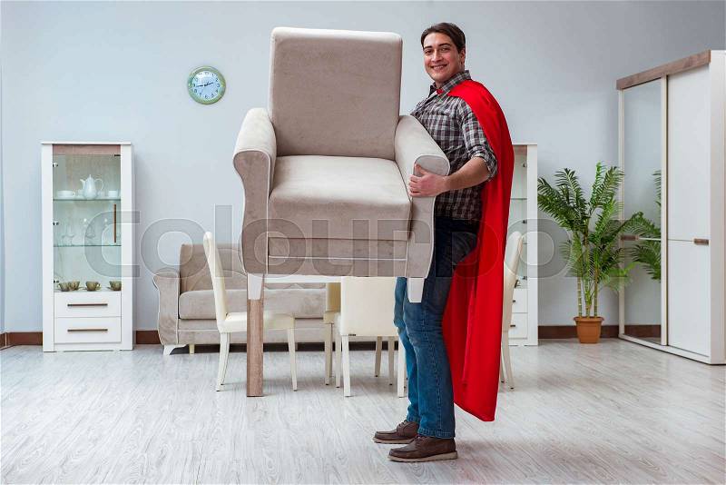 Super hero moving furniture at home, stock photo