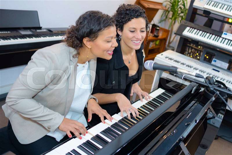 Women singing while playing piano, stock photo