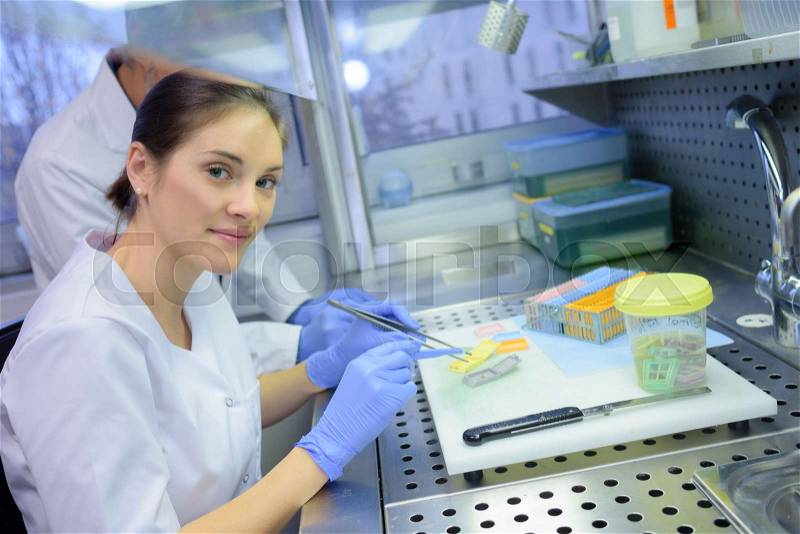 Female lab technician holding tweezers, stock photo