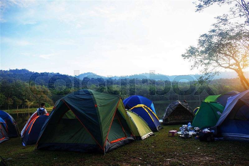 Tent camping leisure travelers at river in the morning sunlight, stock photo