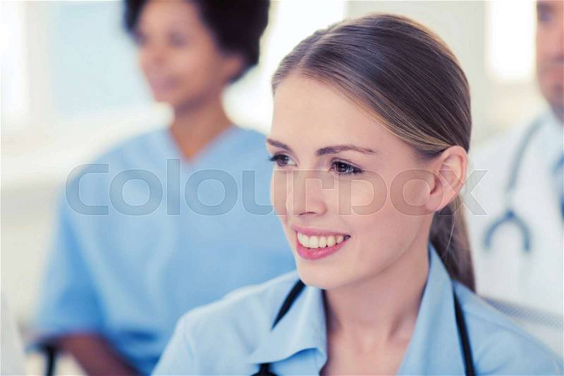 Clinic, profession, people and medicine concept - happy female doctor over group of medics meeting at hospital, stock photo