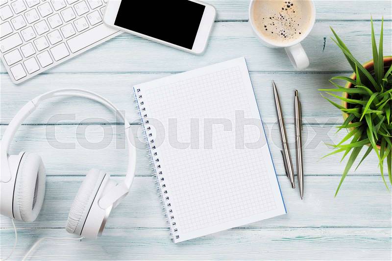 Notepad, headphones, phone and pc on wooden desk table. Top view with copy space, stock photo