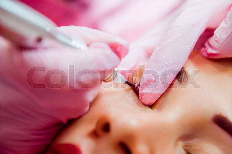 Close up Permanent make up (tattoo). Medical Cosmetologist applying permanent makeup on eyes. Selective focus, stock photo