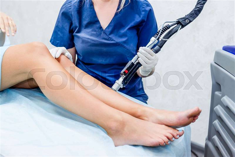 Close up Laser hair removal in the beauty salon. Woman having legs epilation. Laser hair removal equipment in the background, stock photo