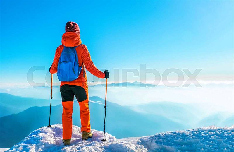 Woman hiker successful on mountain peak summit in winter mountains, stock photo