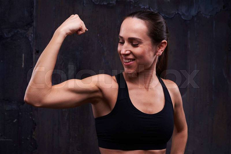 Close-up of trained woman posing at the camera. Self-controlled fitness woman with perfect body performing pumping up. The concept of sport and healthcare , stock photo