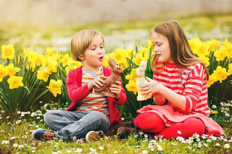 Cute little kids, big sister and small brother, with chocolate Easter bunnies celebrating traditional feast. Family, holiday, spring , carefree childhood concept, stock photo
