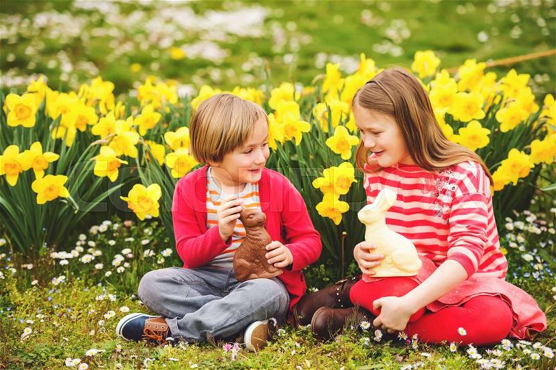 Cute little kids, big sister and small brother, with chocolate Easter bunnies celebrating traditional feast. Family, holiday, spring , carefree childhood concept, stock photo