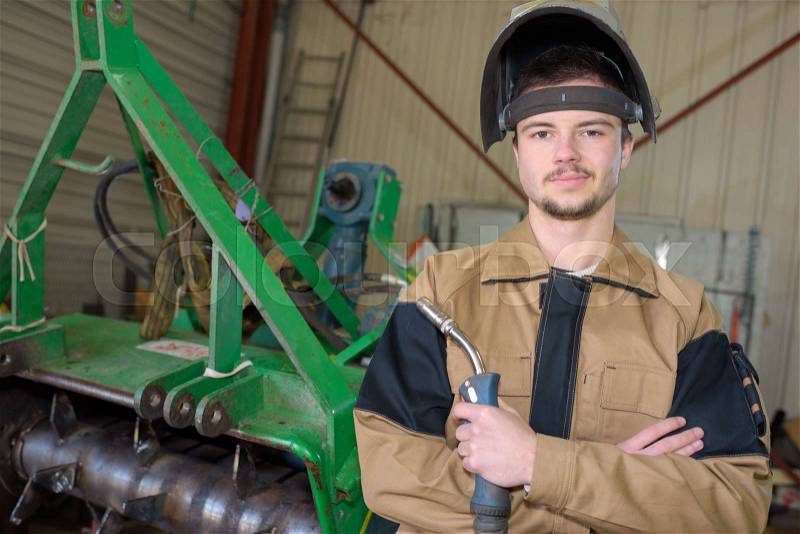 Happy apprentice welder at work in the plant, stock photo