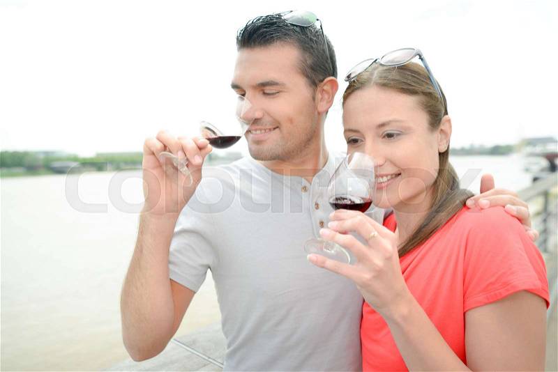 Couple smelling the bouquet of their glasses of wine, stock photo