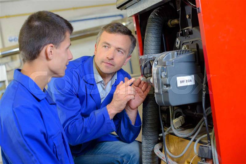 Tradesman explaining machinery to apprentice, stock photo